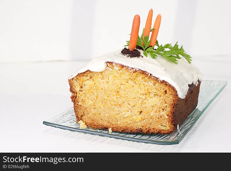 Delicious moist carrot cake decorated with chocolate cookie crumbs baby carrots and carrot leaves. Delicious moist carrot cake decorated with chocolate cookie crumbs baby carrots and carrot leaves