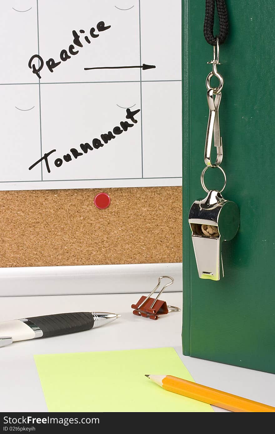 A silver whistle on a green notebook next to a schedule of the tournament. A silver whistle on a green notebook next to a schedule of the tournament.