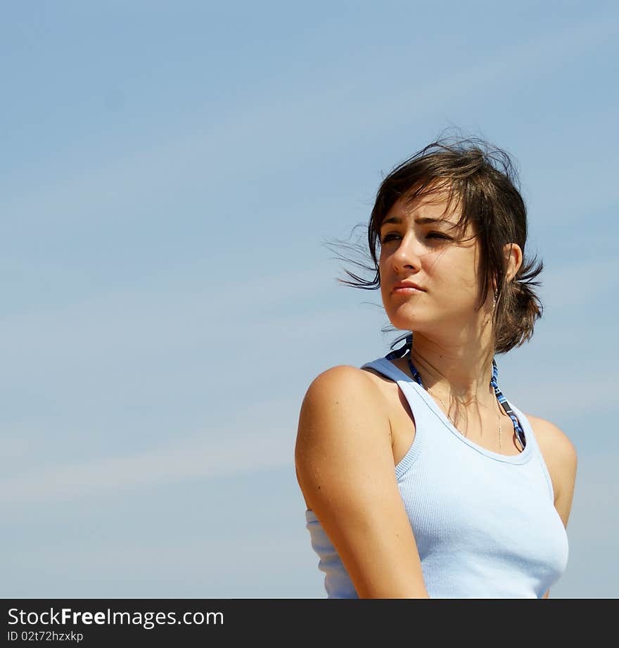 Portrait of a young beautiful woman near a seashore looking somewhere away in the distance. Portrait of a young beautiful woman near a seashore looking somewhere away in the distance