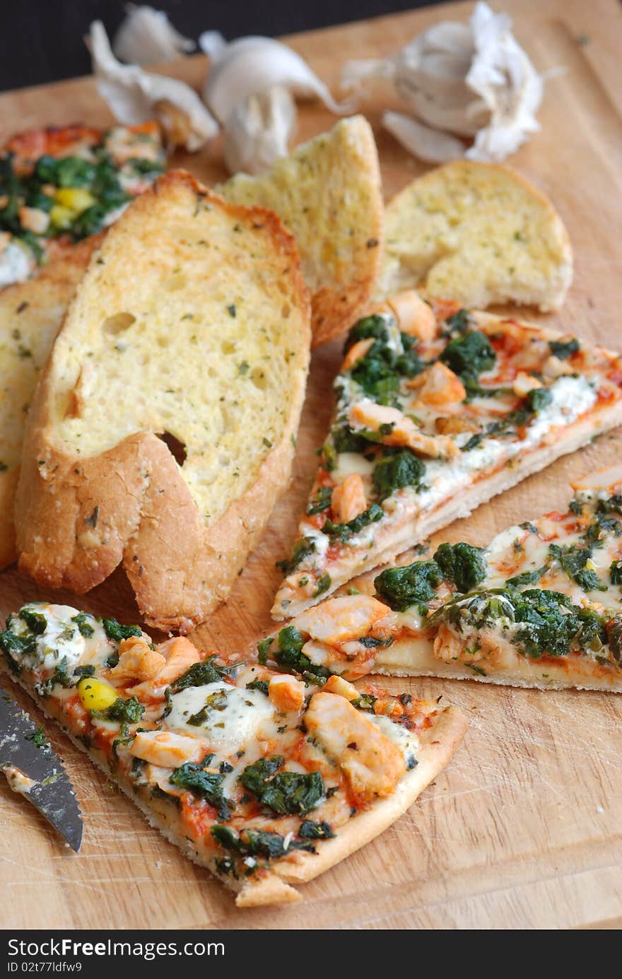 Slices of pizza with garlic bread on wooden board