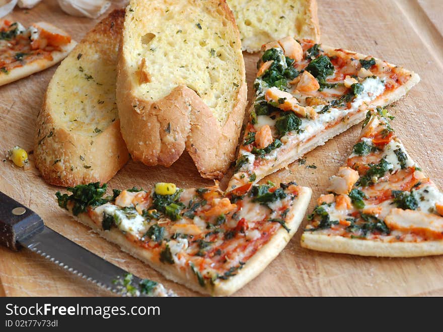 Slices of pizza with garlic bread on wooden board