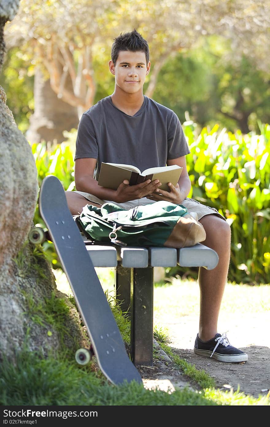 Student with skateboard and backpack at a park. Student with skateboard and backpack at a park