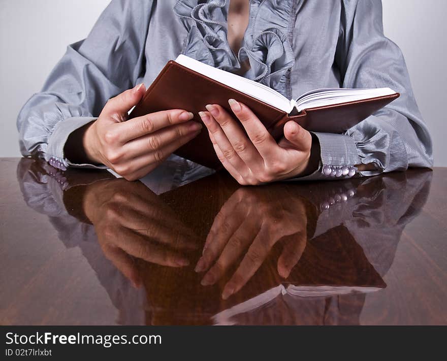 Businesswoman sitting at the desk and holding notepad in hands