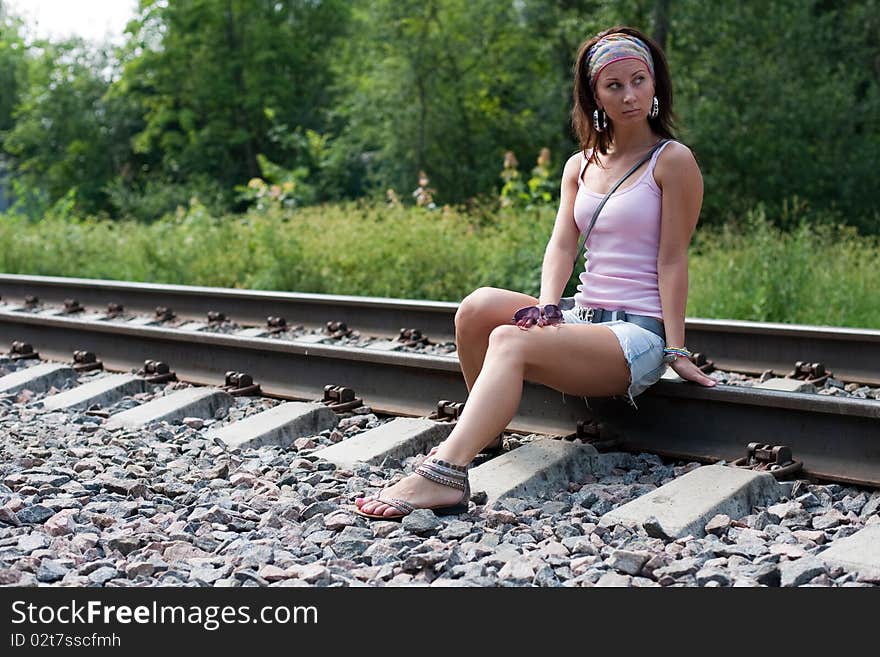 Slim lady is sitting on a railroad