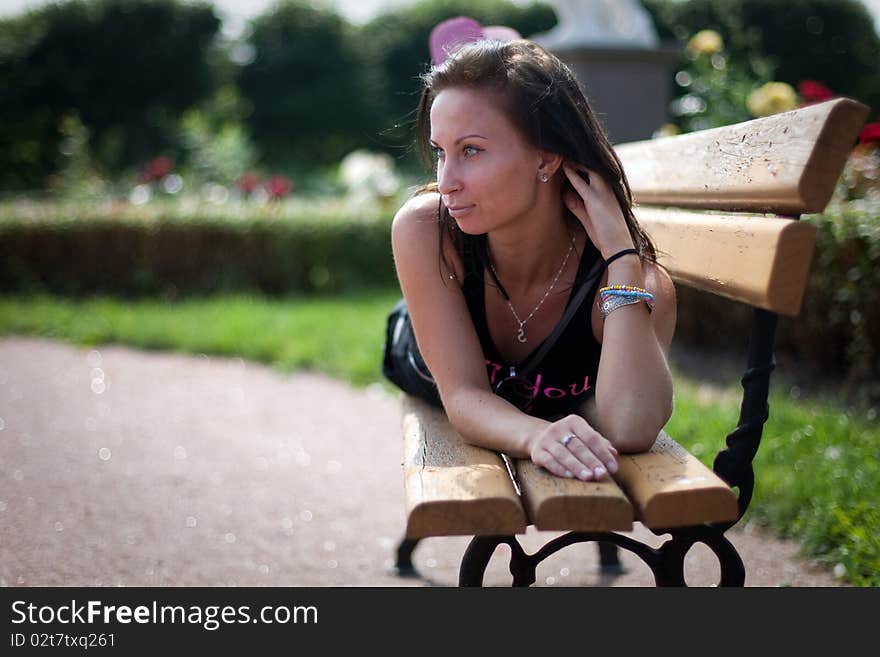 Pretty smiling girl is relaxing on a brench in the park. Pretty smiling girl is relaxing on a brench in the park