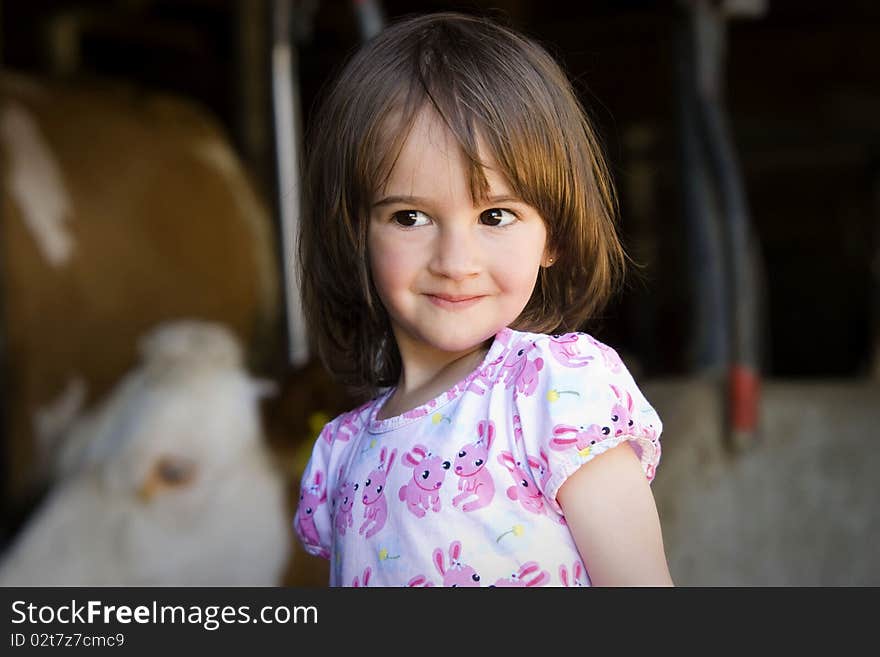 Portrait of a glittle girl with cow in background. Portrait of a glittle girl with cow in background