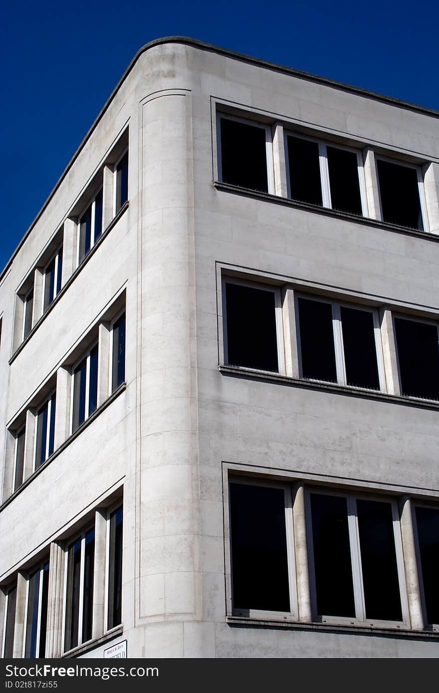 Corner of a white concrete office building under a clear sky. Corner of a white concrete office building under a clear sky.