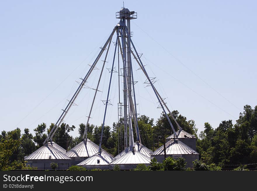 Dome roofed steel buildings grouped into a circle with a tower in the center and all connected to the center tower with pipes and cables, farming, grain bins, agriculture, environment. Dome roofed steel buildings grouped into a circle with a tower in the center and all connected to the center tower with pipes and cables, farming, grain bins, agriculture, environment