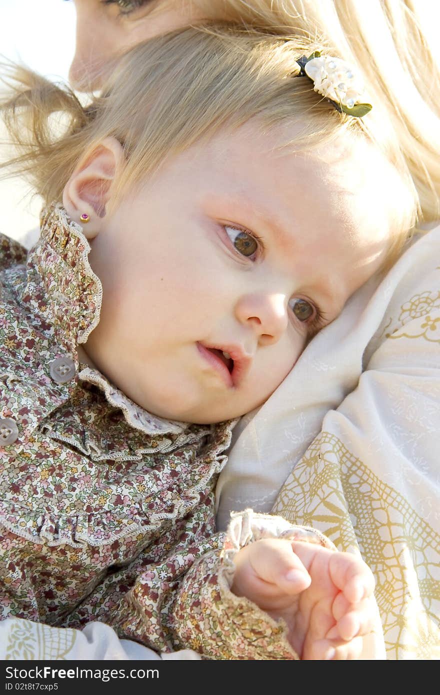 The little girl is upset and lays on a breast at mum. The little girl is upset and lays on a breast at mum