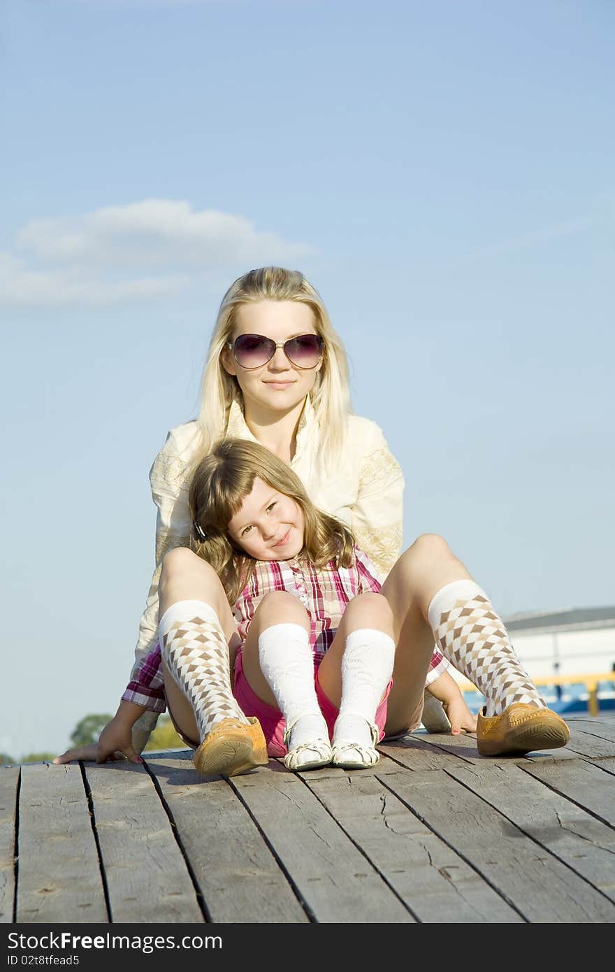 The girl smiles and sits before the woman against the dark blue sky. The girl smiles and sits before the woman against the dark blue sky