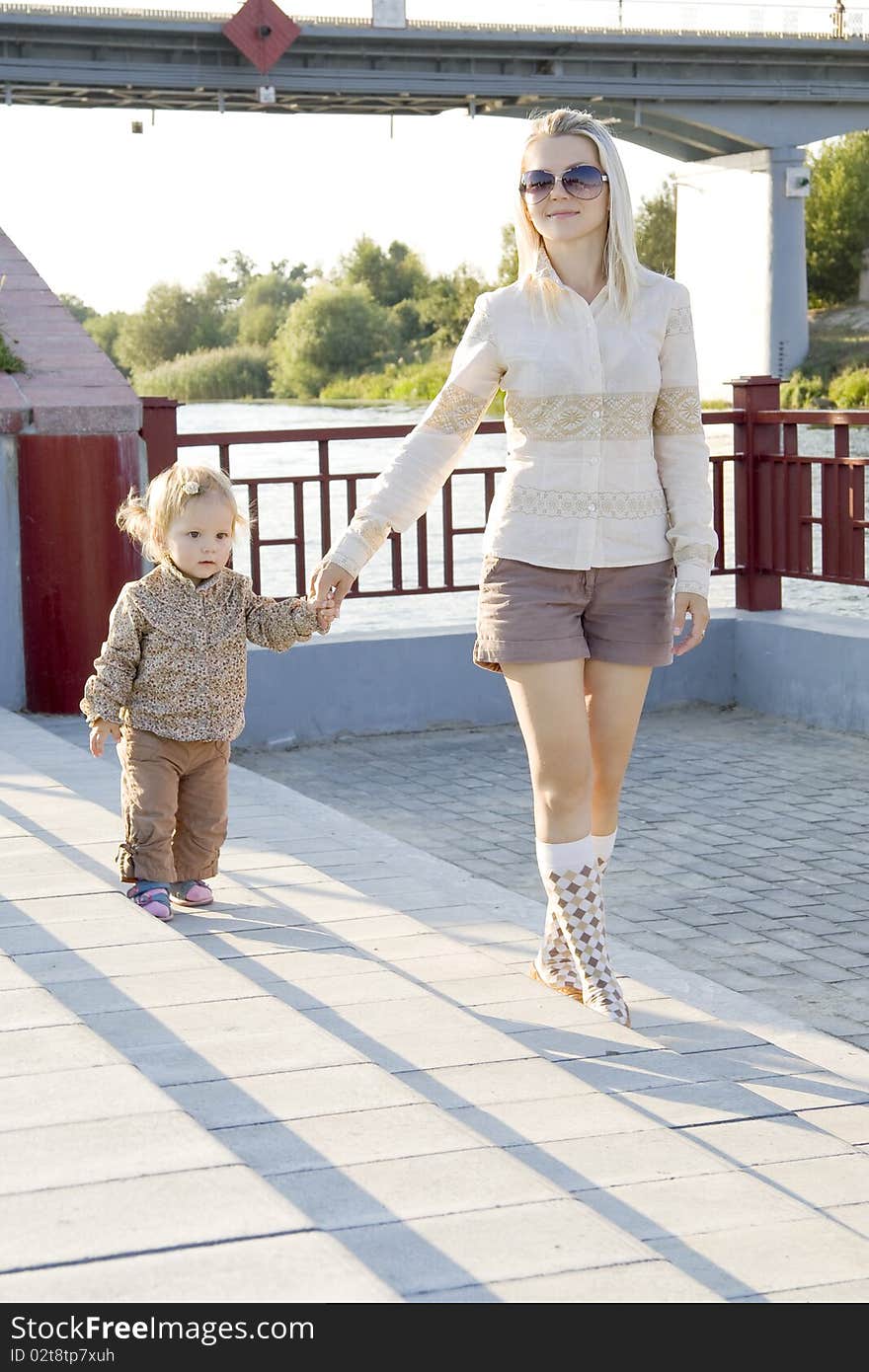 The woman with the child having joined hands walks on quay. The woman with the child having joined hands walks on quay