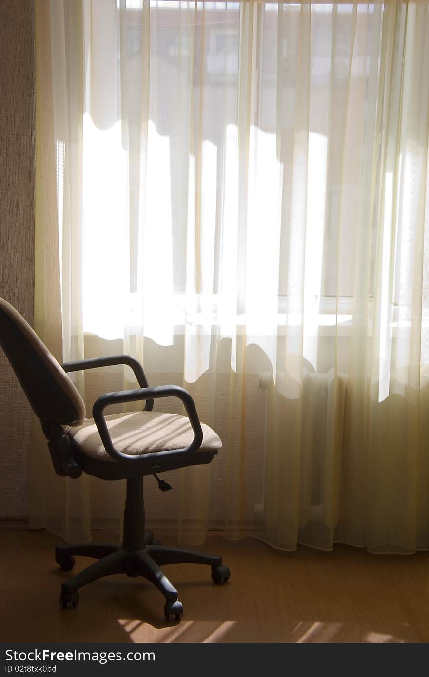 The chair on wheels costs in a room near a window in sunlight beams