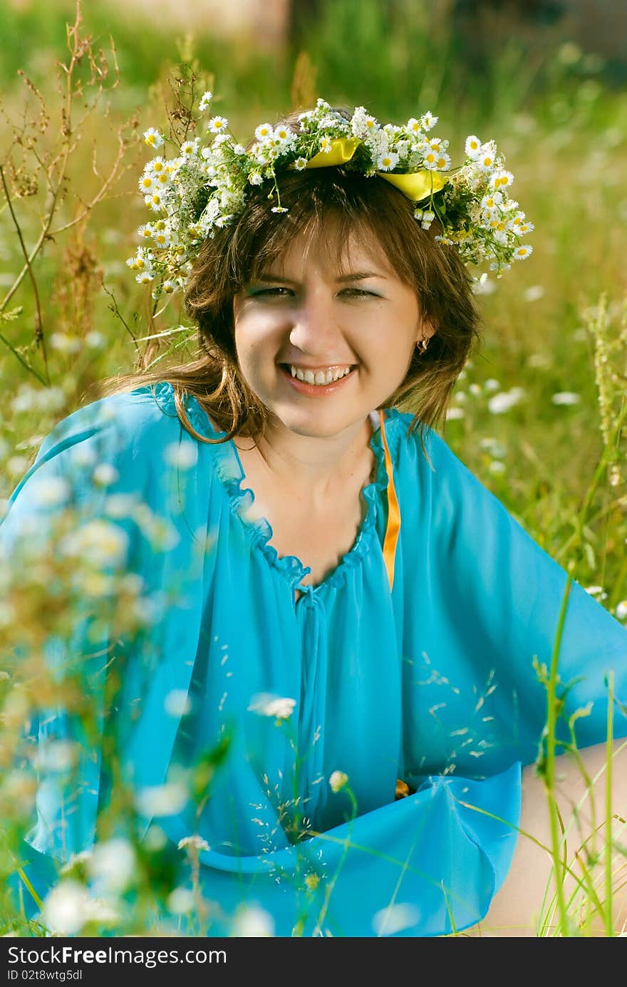 Beautiful girl sitting in a field with a bouquet of flowers