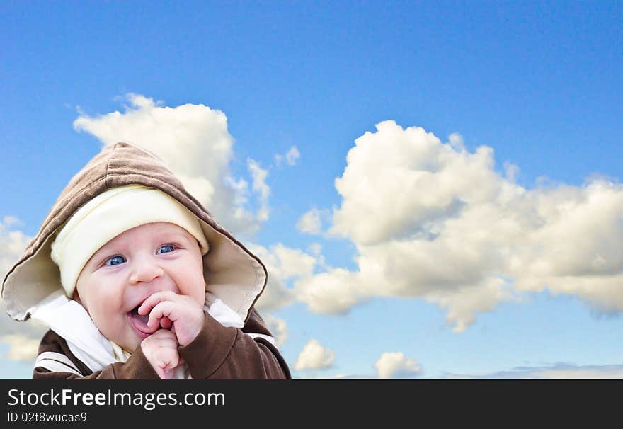 the baby holding hands and laughing on sky background. the baby holding hands and laughing on sky background