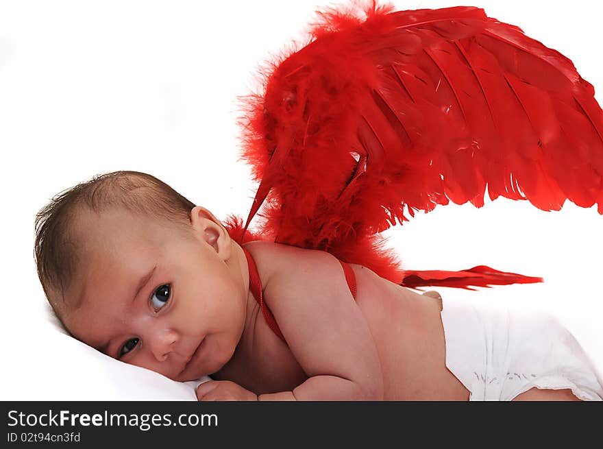 Baby in studio smiling and wearing red angle wings. Baby in studio smiling and wearing red angle wings