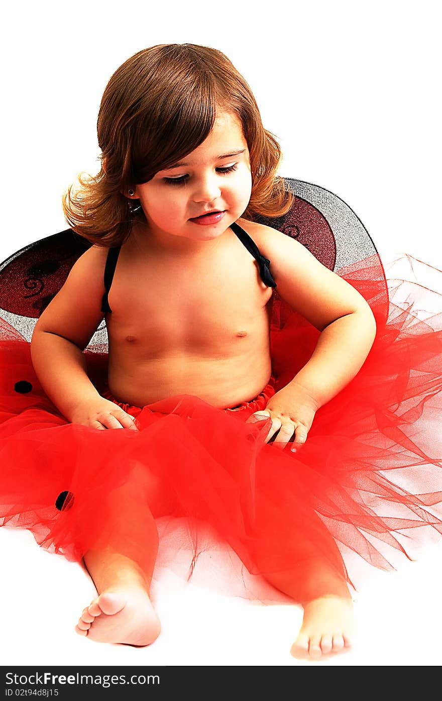 Little girl playing and smiling in studio wearing red angle wings. Little girl playing and smiling in studio wearing red angle wings