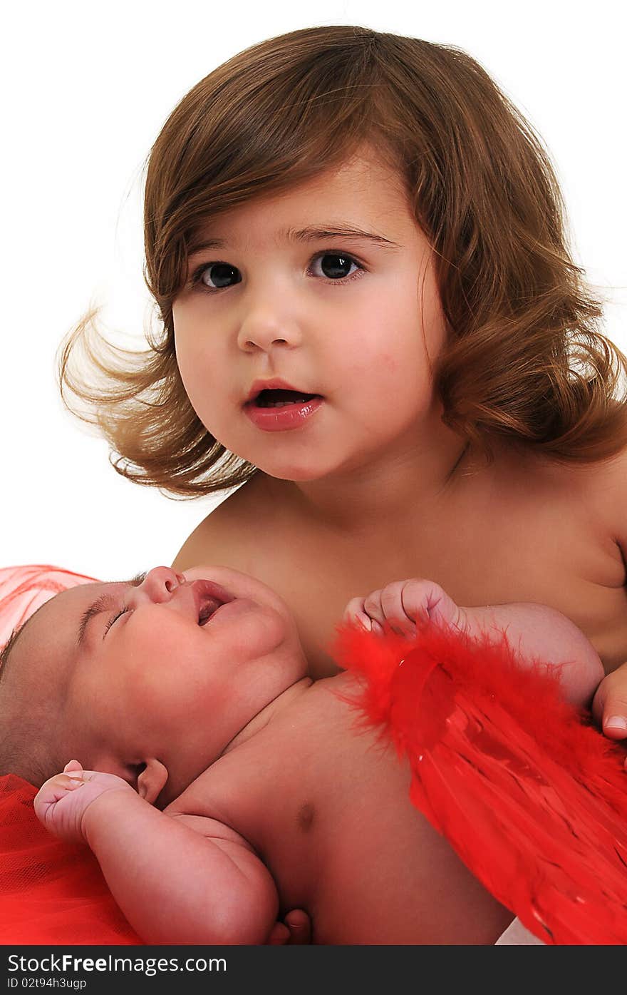 Two sisters playing and smiling in studio wearing red angle wings. Two sisters playing and smiling in studio wearing red angle wings