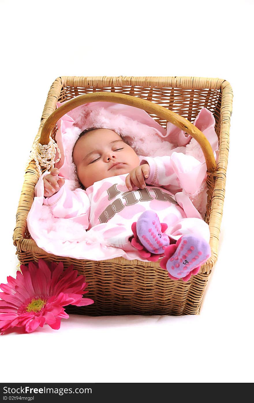 Newborn baby girl laying in a brown basket, white beads and big pink flower. Newborn baby girl laying in a brown basket, white beads and big pink flower