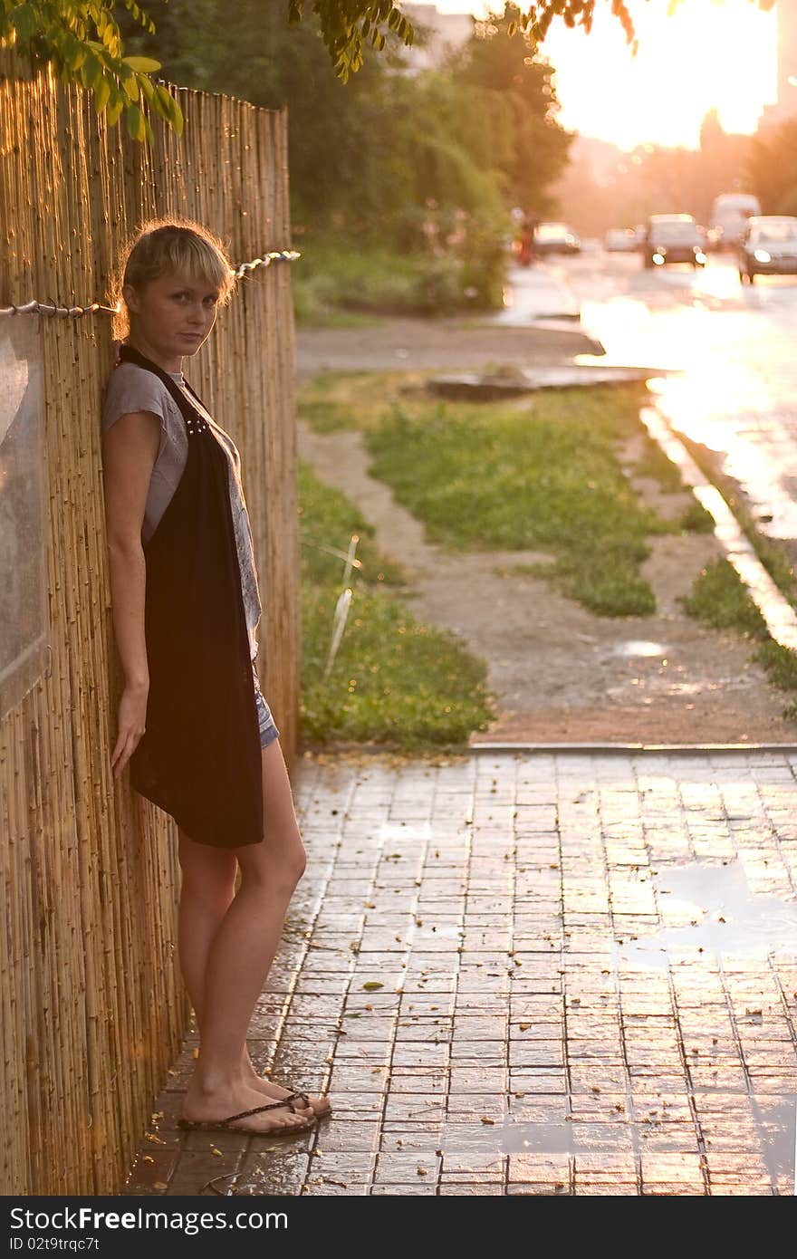 City girl staniding against the wall at sunset