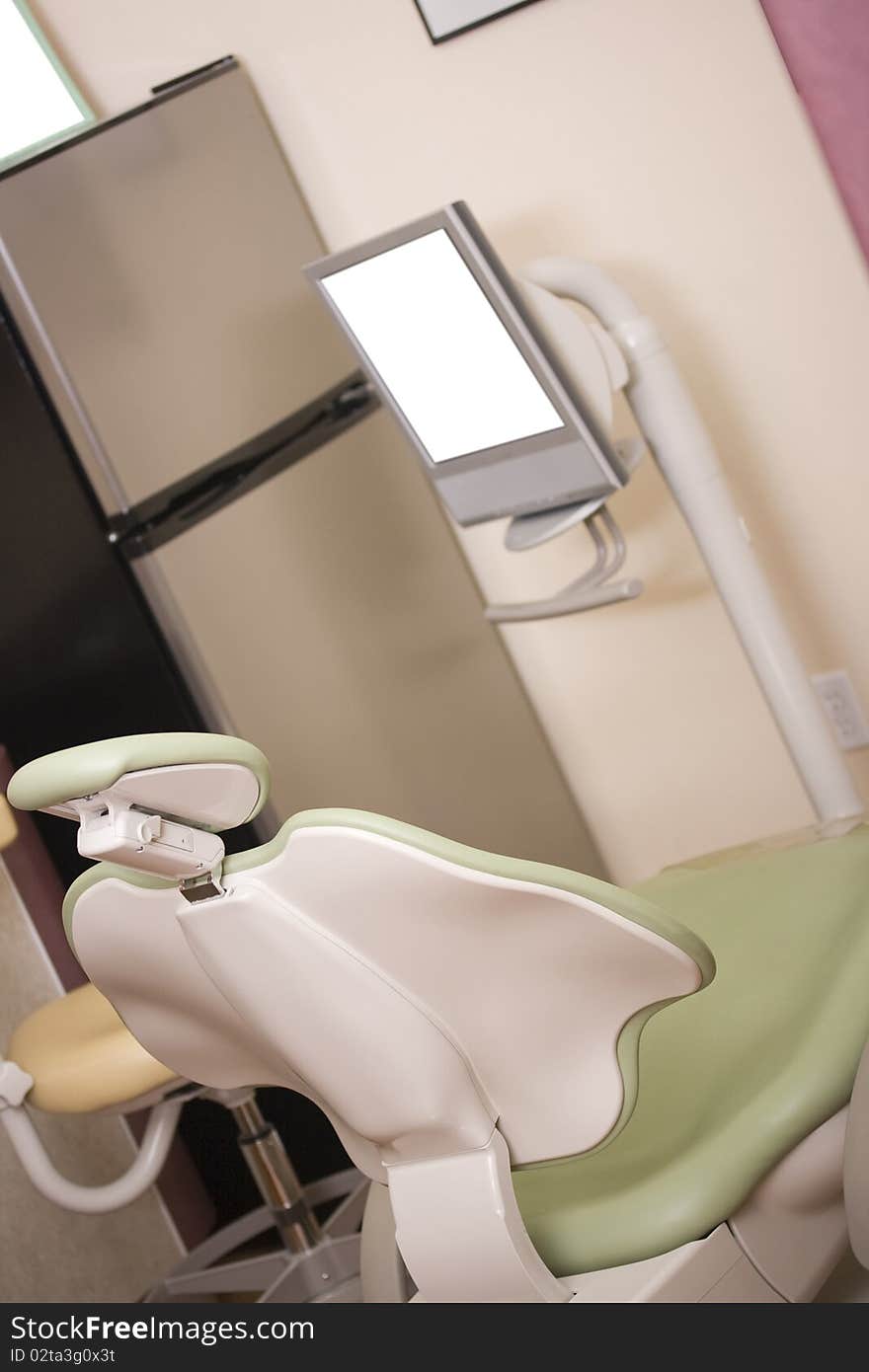 Dentist chair next to a monitor in a dental clinic.