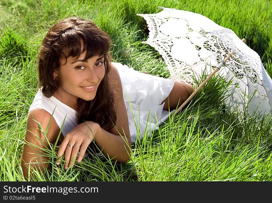 Young  beautiful girl  with sun umbrella relaxing in the fresh green grass. Young  beautiful girl  with sun umbrella relaxing in the fresh green grass