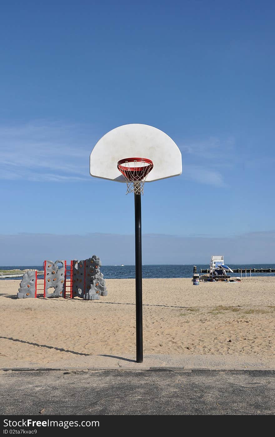 Baskeball hoop rock climbing activity center and lifeguard station on beach under clear blue sky. Baskeball hoop rock climbing activity center and lifeguard station on beach under clear blue sky