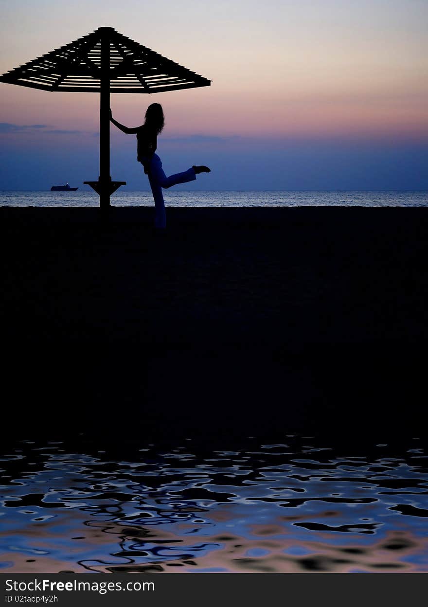 Beach umbrella and the girl silhouette on sunset. Beach umbrella and the girl silhouette on sunset