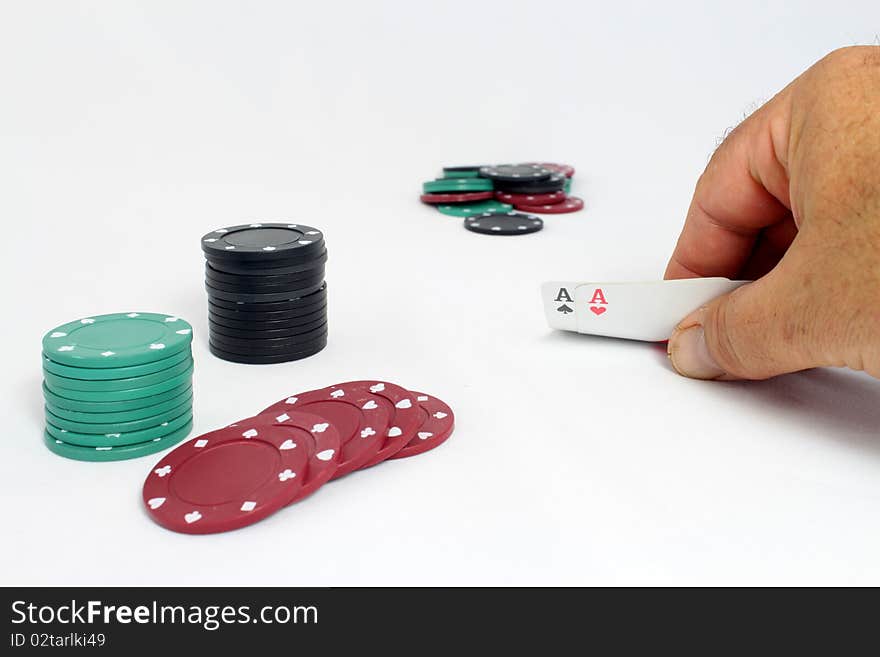 A game of poker, with a hand showing a pair of aces, player's chips close and pot out of focus in background. A game of poker, with a hand showing a pair of aces, player's chips close and pot out of focus in background