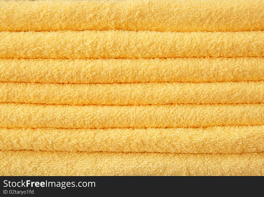 Yellow terry towels stacked in a pile.