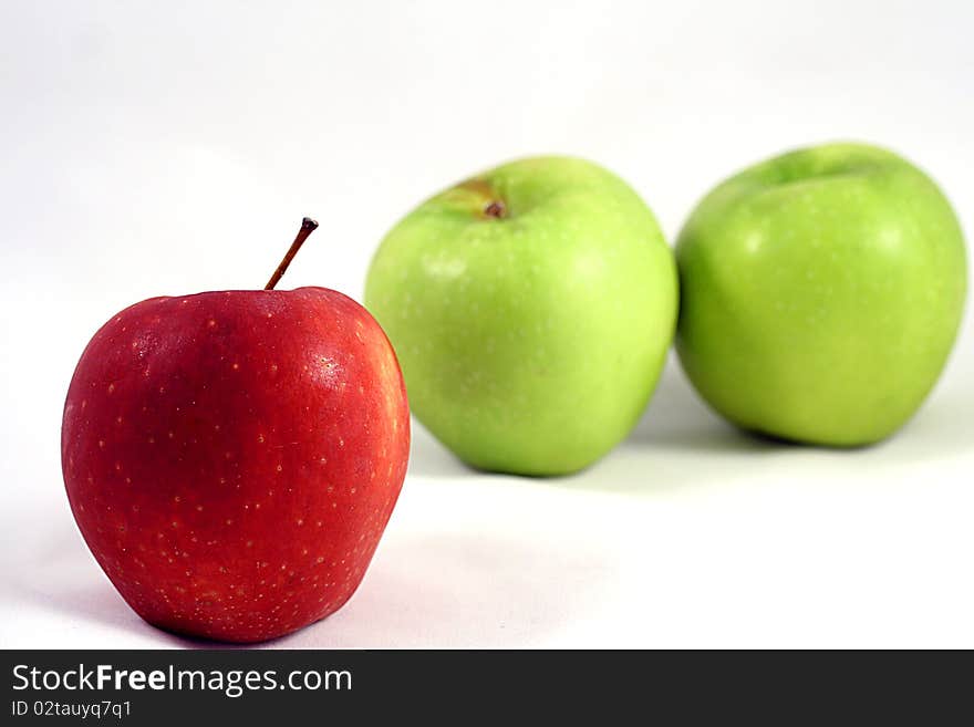 A red apple in front of two green ones. A red apple in front of two green ones.