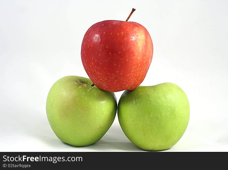 A red apple on top of two green ones. A red apple on top of two green ones.