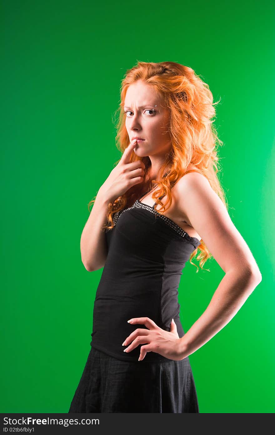 Beautiful red-haired woman with a worried look in black sarafan on a green background. Beautiful red-haired woman with a worried look in black sarafan on a green background