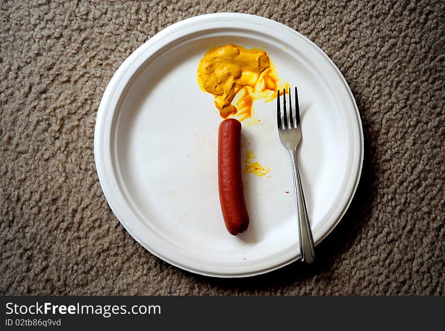 Hotdog and mustard on the carpet in a paper plate. Hotdog and mustard on the carpet in a paper plate.