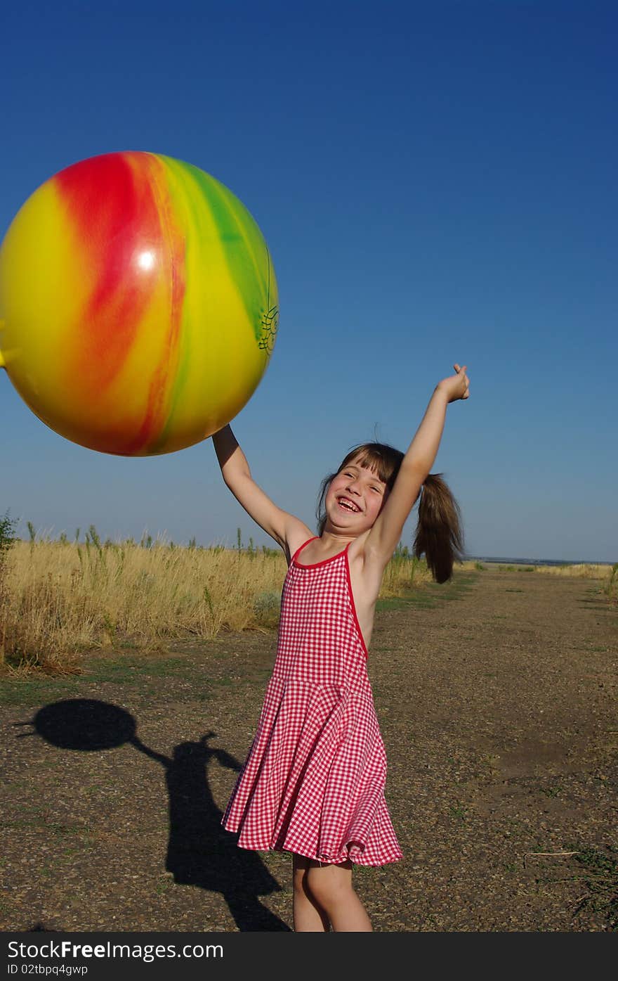 The little girl plays with the big ball. The little girl plays with the big ball