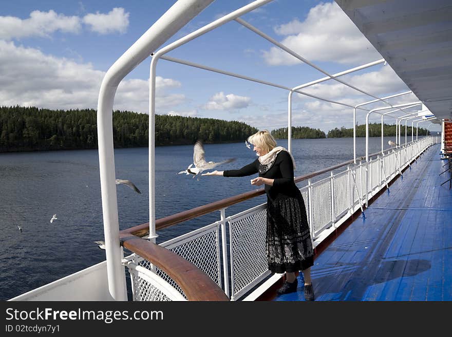 The woman onboard the steam-ship feeds seagulls. The woman onboard the steam-ship feeds seagulls