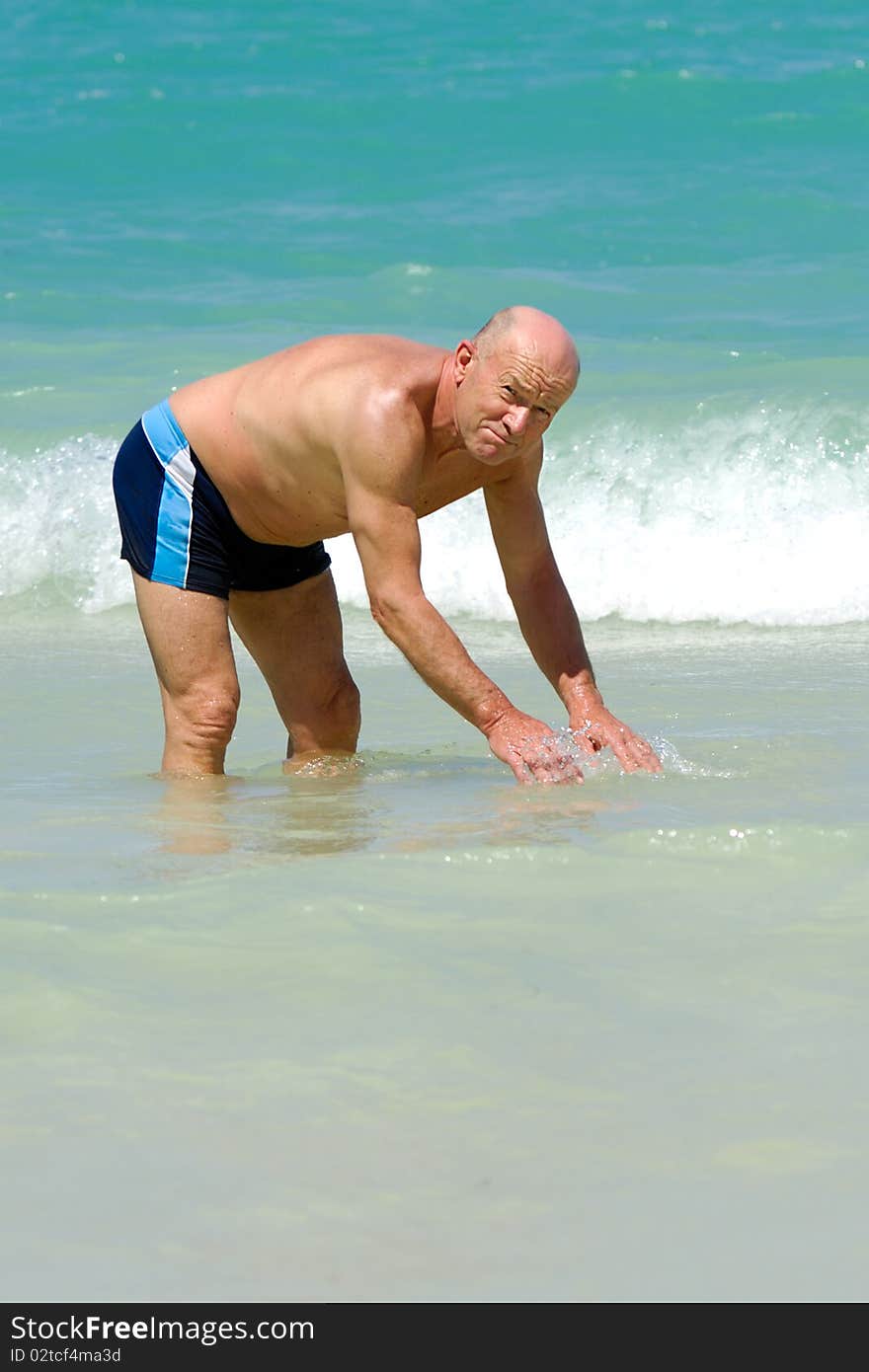 A senior man is standing in the water about to swim. Beach at Punta Cana, Dominican Republic. A senior man is standing in the water about to swim. Beach at Punta Cana, Dominican Republic.