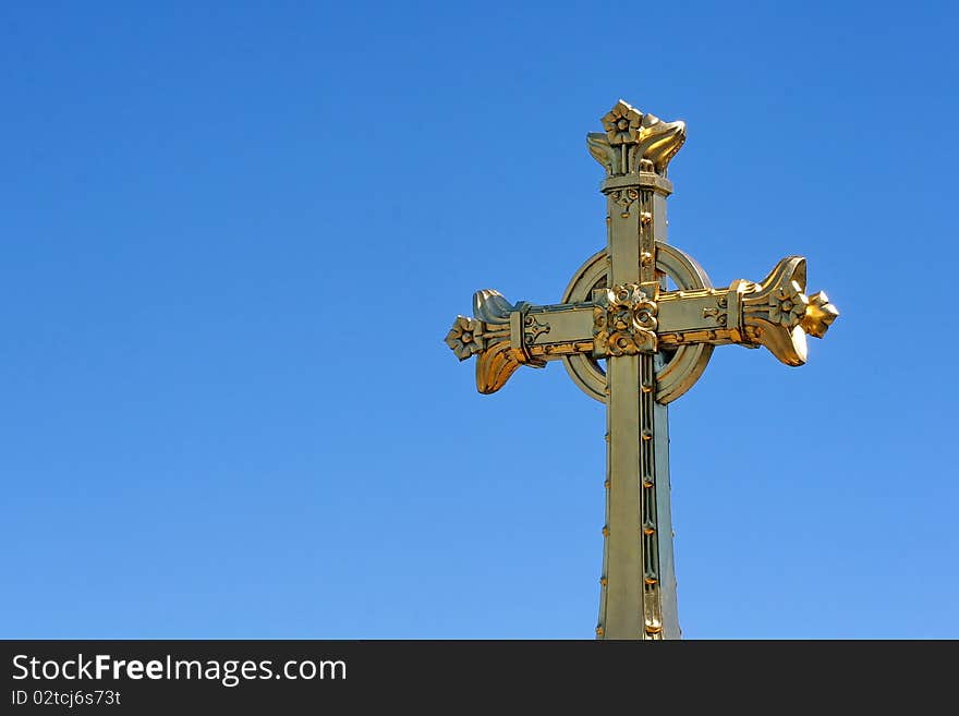 The golden cross on the Rosary Basilica in the holy catholic city of Lourdes in France with ancient castle in the background. The golden cross on the Rosary Basilica in the holy catholic city of Lourdes in France with ancient castle in the background.