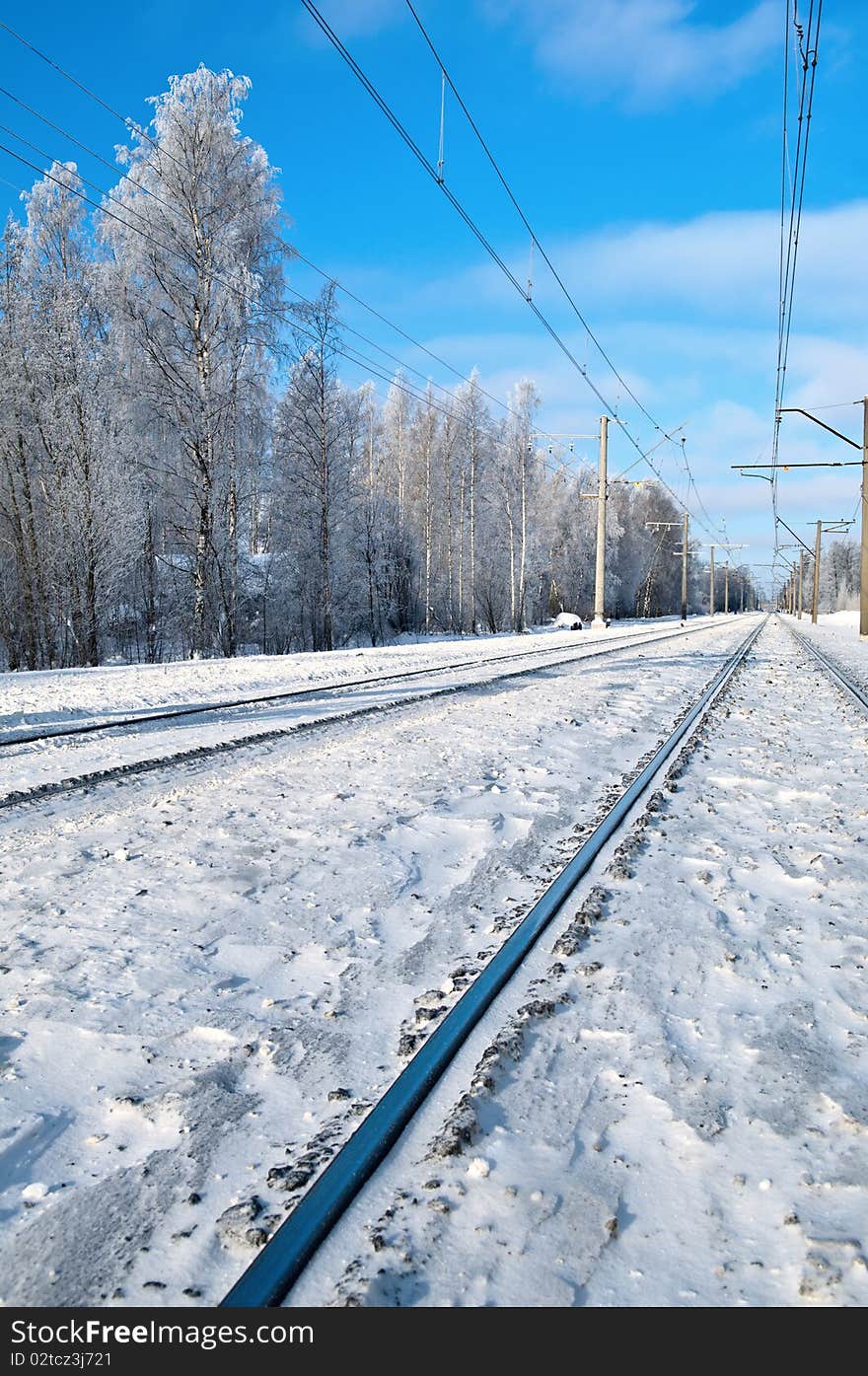 Railroad track against a background of snow-covered tree and blue sky. Railroad track against a background of snow-covered tree and blue sky.