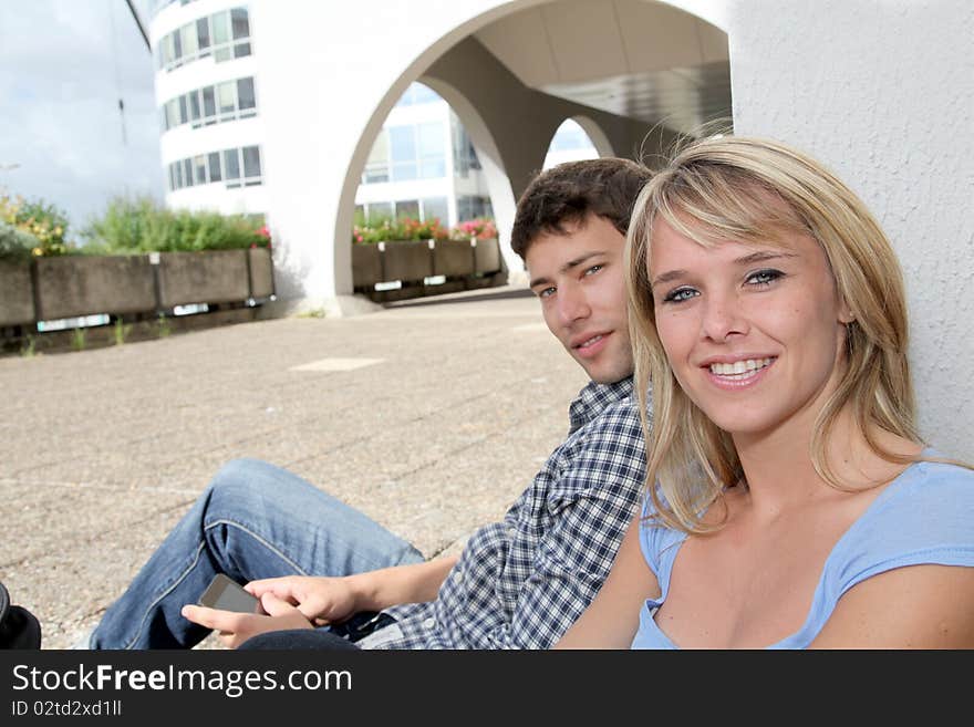 Young couple of students sitting in campus yard. Young couple of students sitting in campus yard