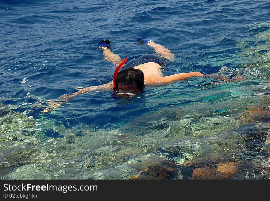 A man snorkeling in the blue sea