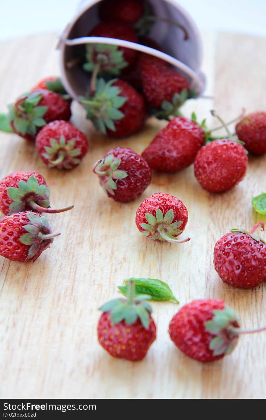 Pink bucket with a strawberry on a wooden board