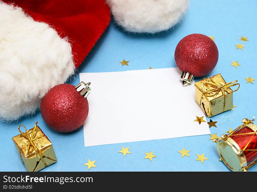 A blank Christmas note with various decorations and a Santa hat.