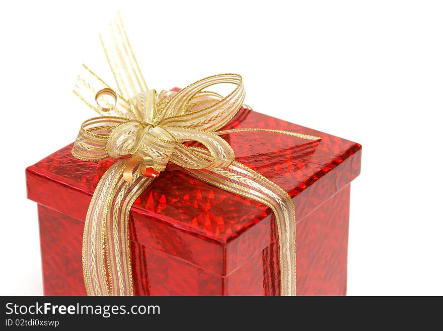 A macro shot of a red gift box with some golden ribbon wrapped around it.