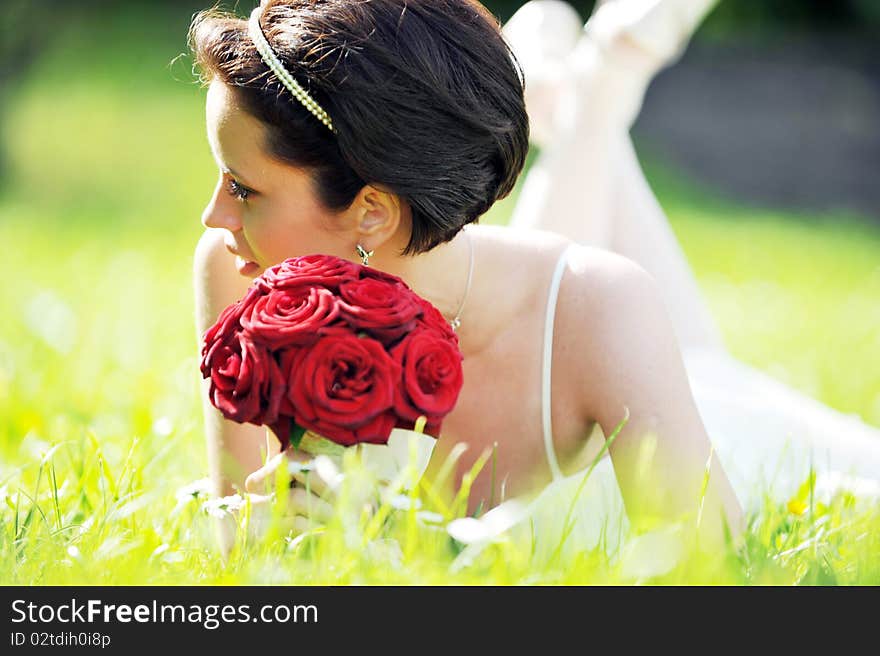 Bride in white dress lying down in  grass.