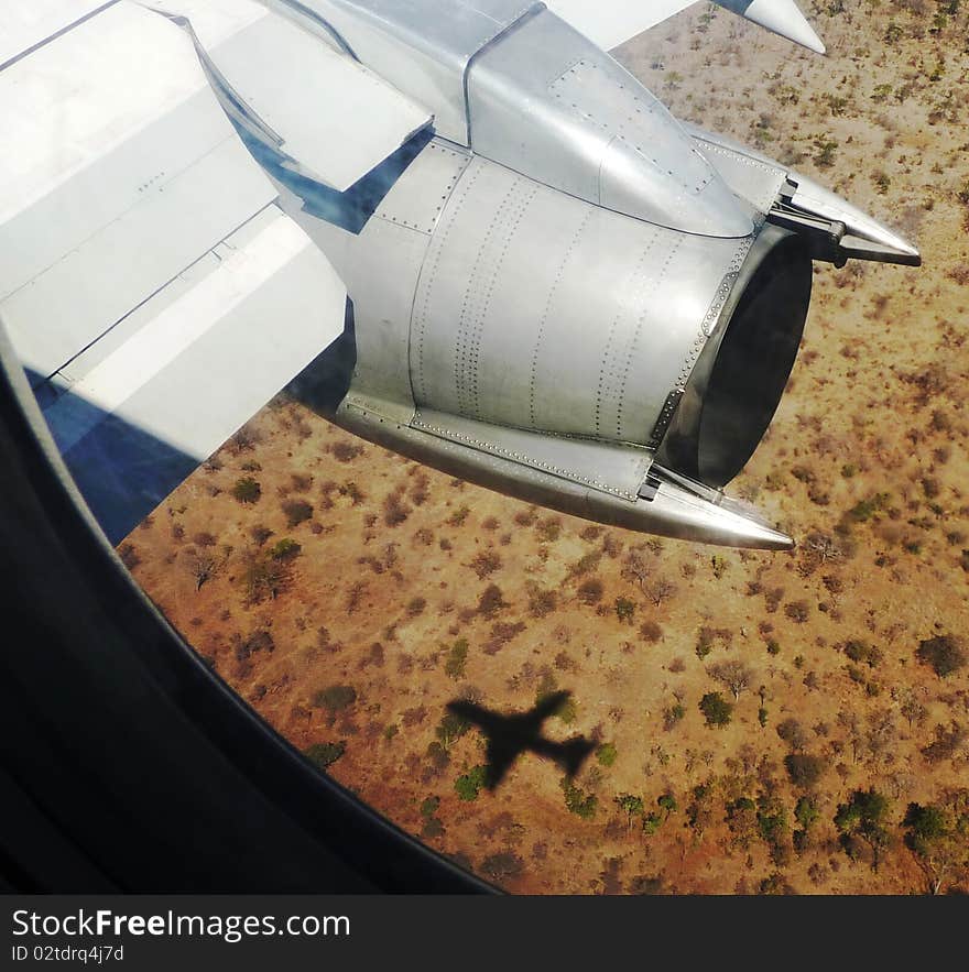 A plane and its shadow flying over a landscape. A plane and its shadow flying over a landscape