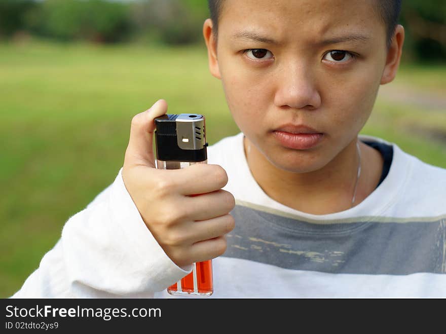 Bald person holding large lighter outdoors with crazy psycho look