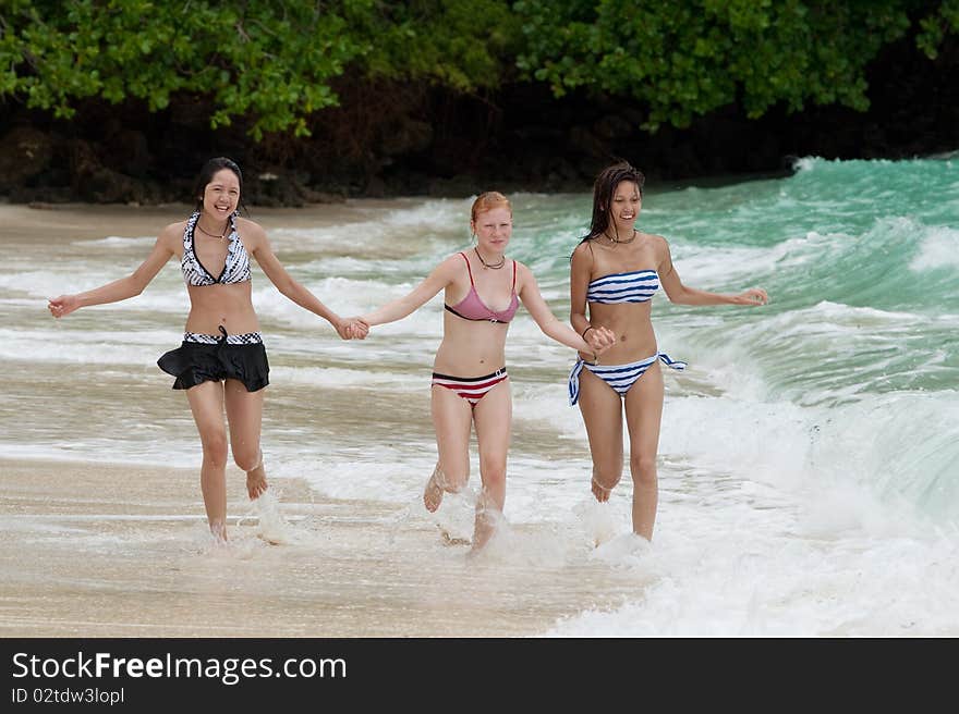 Three girls run on the beach, teenager on vacation at the sea