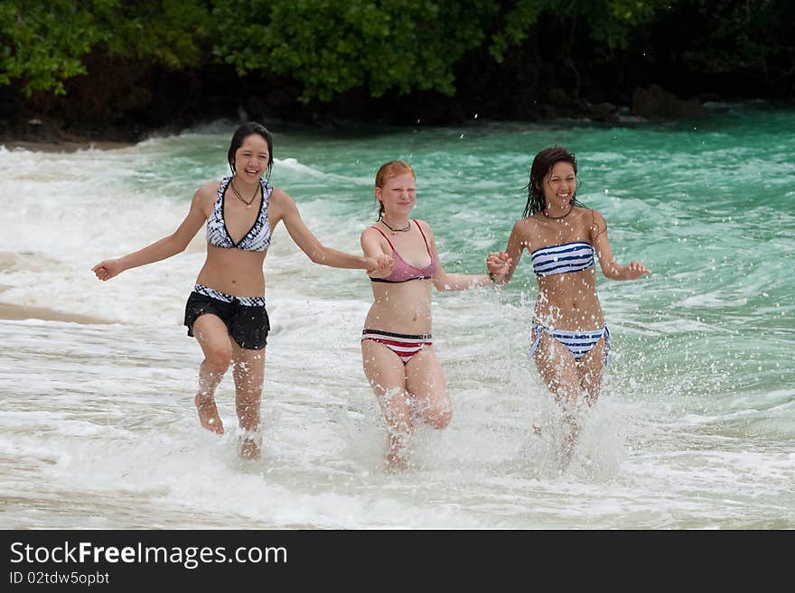 Three girls run on the beach