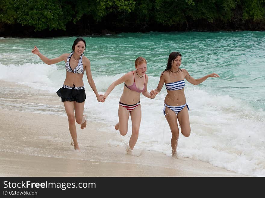 Three girls run on the beach