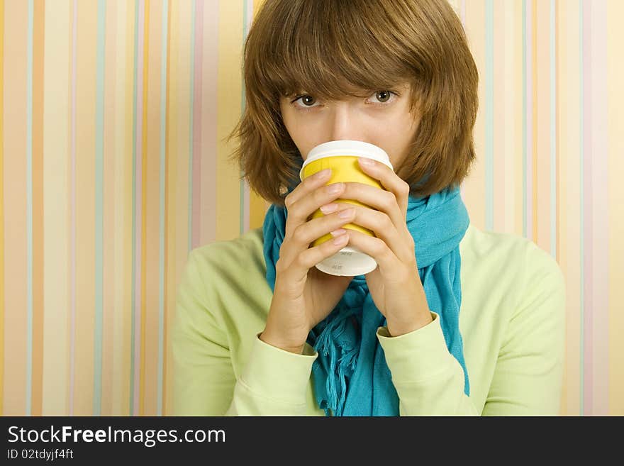 Young girl in a room drinking coffee / tea from a paper cup. Young girl in a room drinking coffee / tea from a paper cup